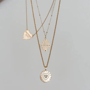 Three gold necklaces with heart pendants on a light gray background
