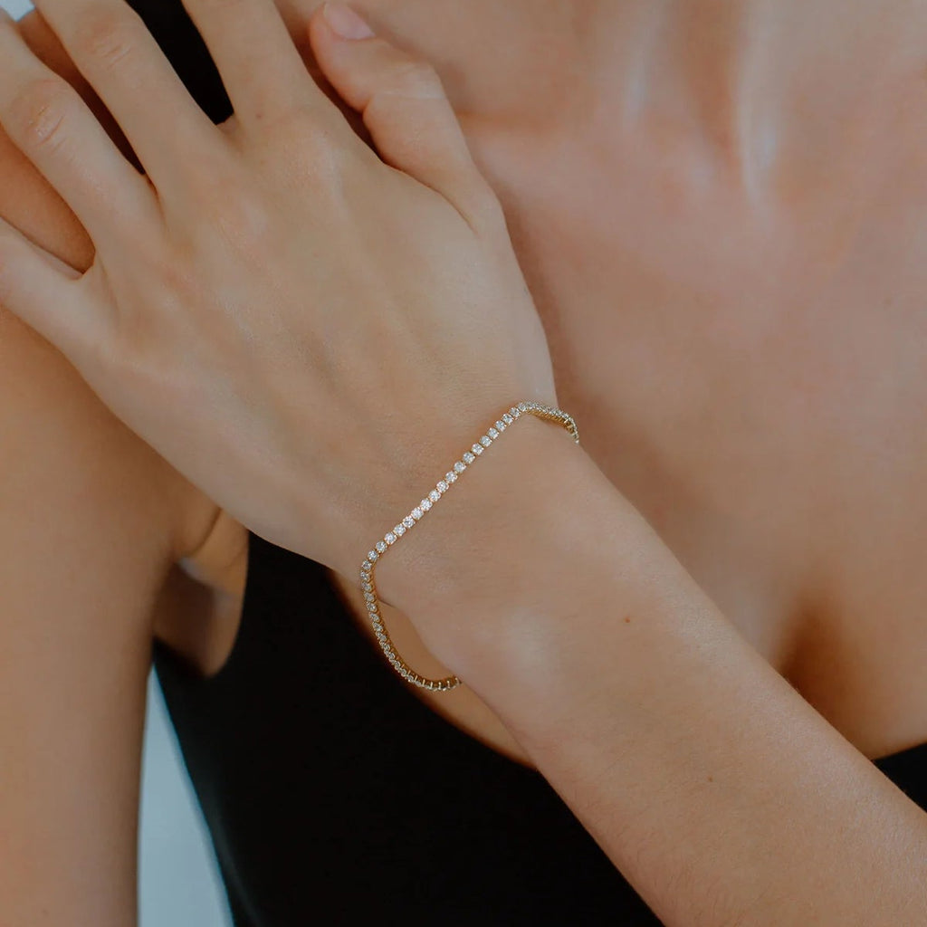 Gold bracelet with clear stones on a white background