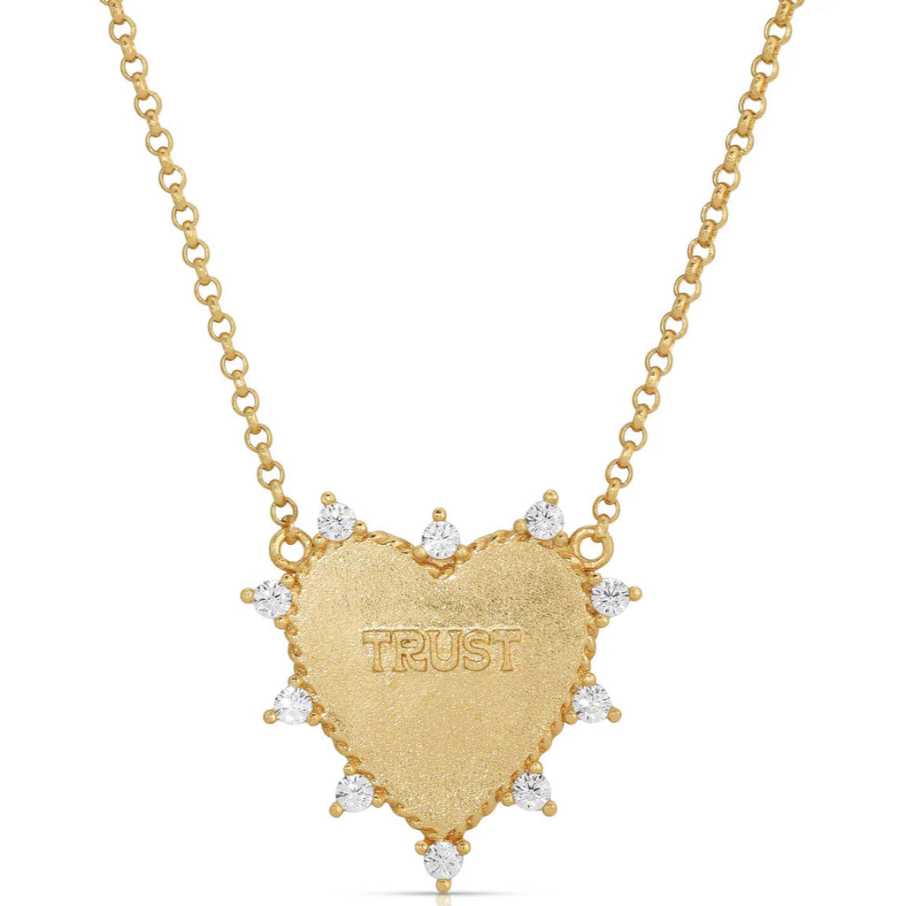 Gold necklace with a heart-shaped pendant inscribed with 'TRUST' on a white background