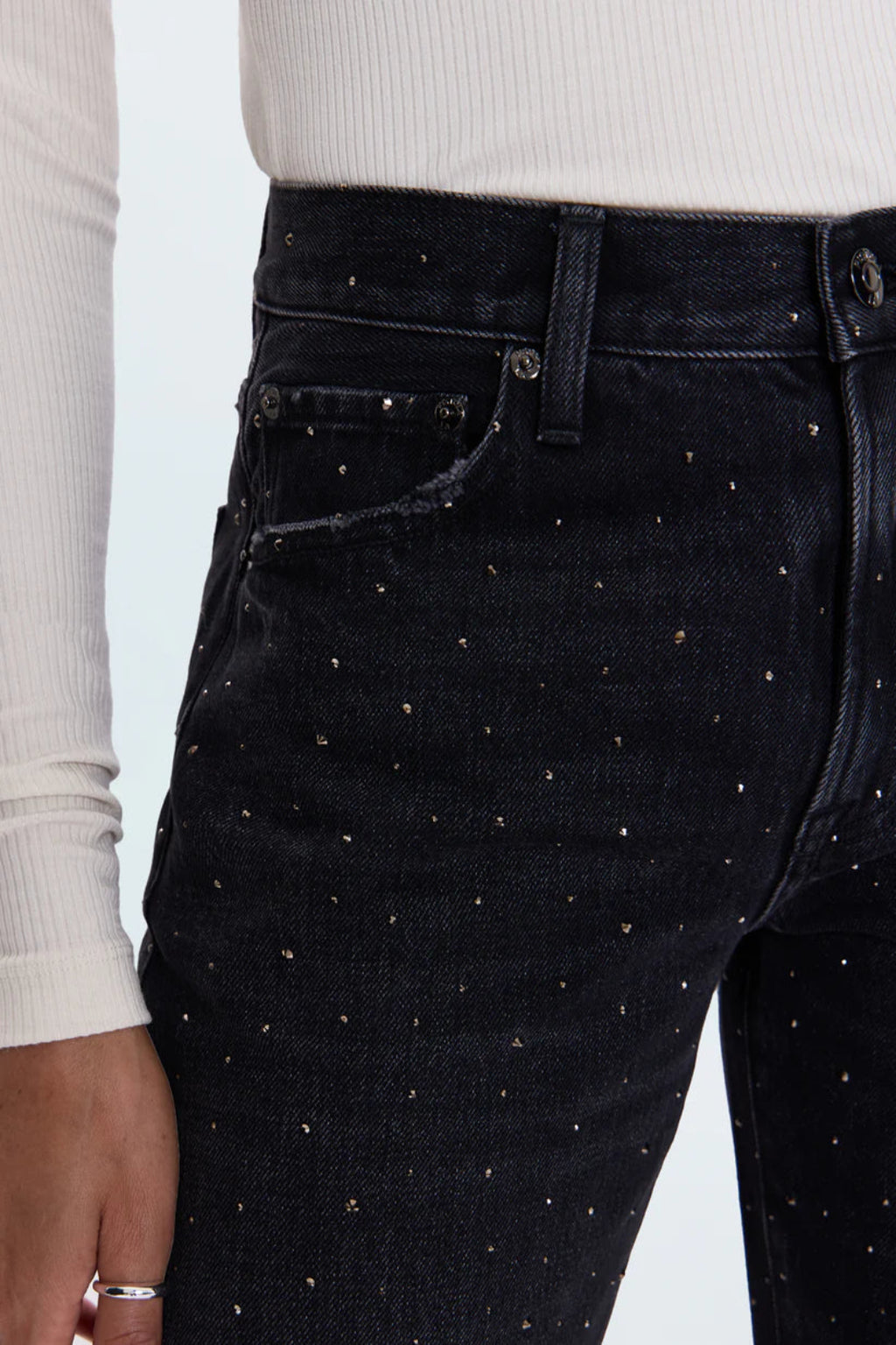 Black jeans with rhinestone embellishments worn by a person on a light gray background.