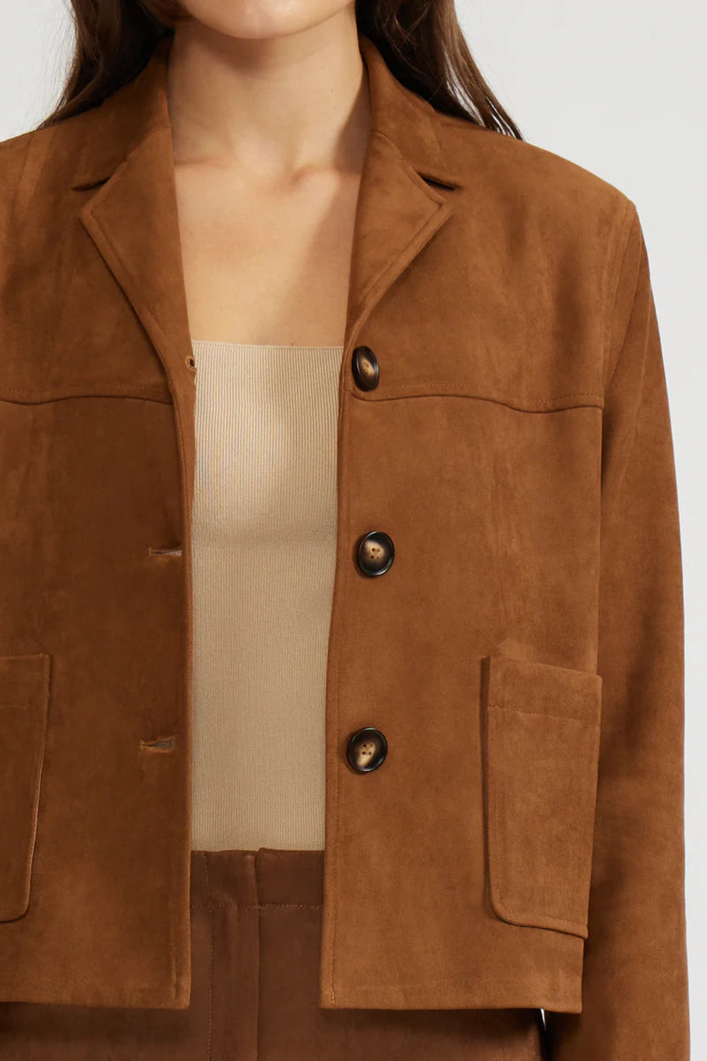 Brown suede jacket worn by a person on a white background.