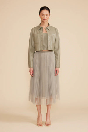 A woman wearing a sage green cropped jacket.