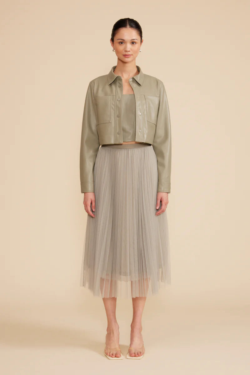 A woman wearing a sage green cropped jacket.