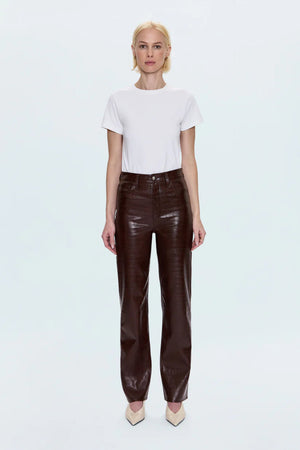 Woman wearing a white shirt with brown croc pants and cream heels. 