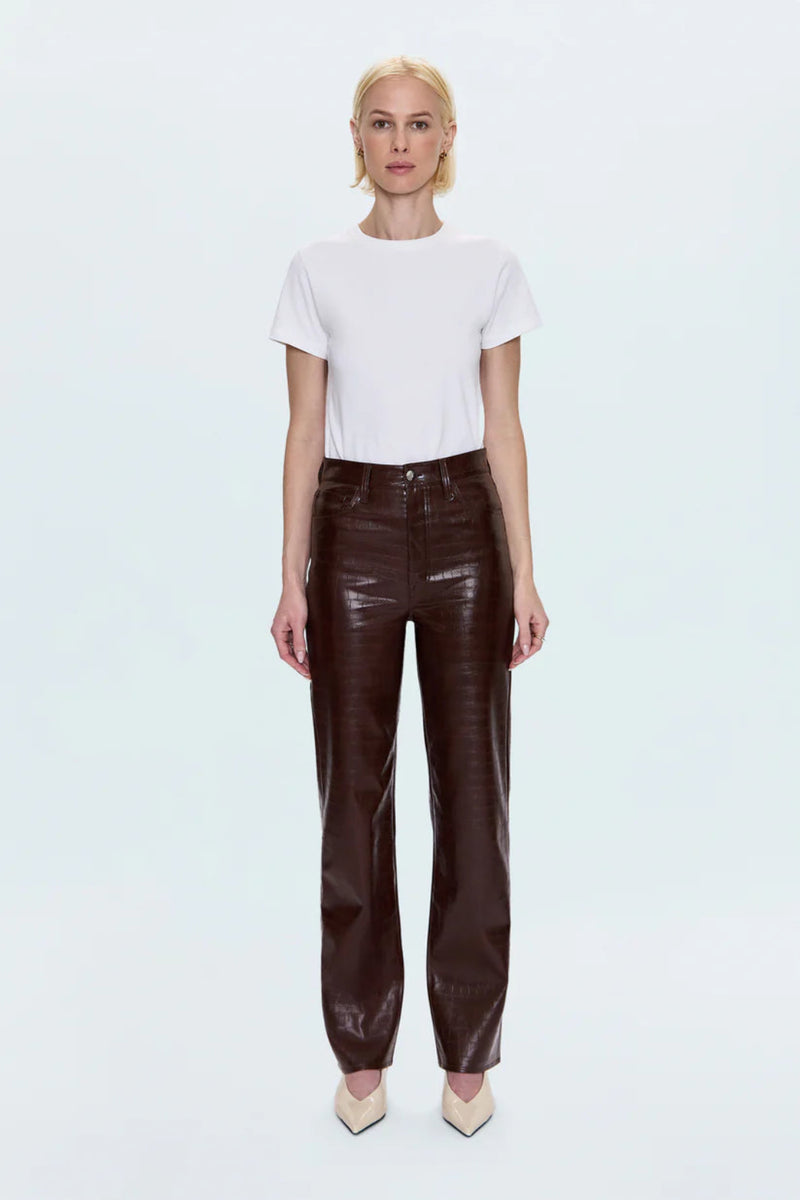 Woman wearing a white shirt with brown croc pants and cream heels. 