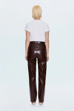 Person wearing a white t-shirt and brown leather pants on a light gray background.