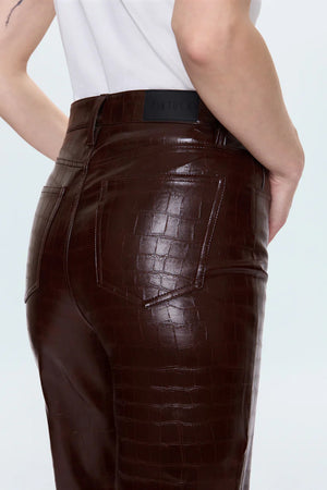 Brown leather pants worn by a person on a light gray background.