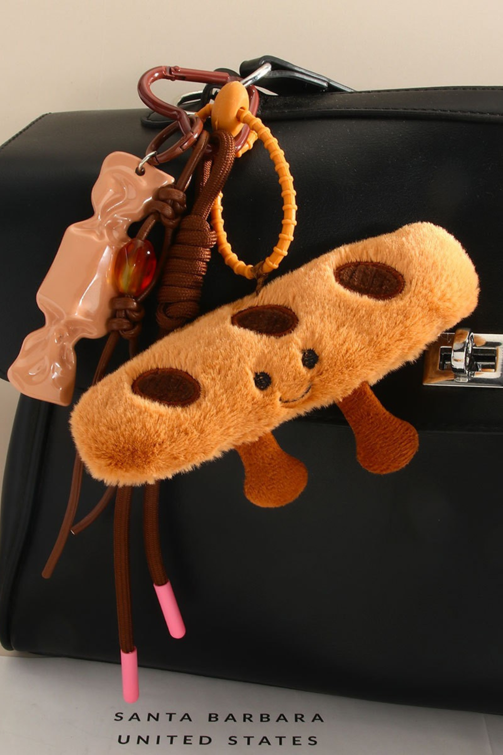 Bag charm of a baguette against a black purse. 