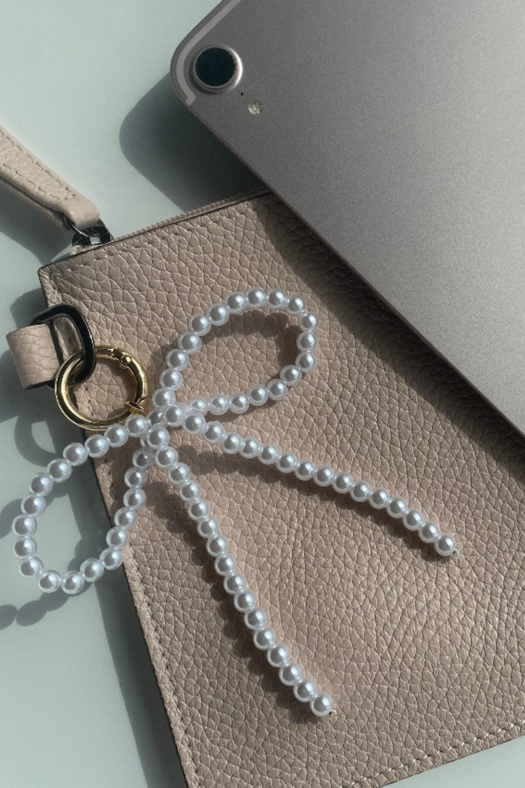 A pearl bow bag charm clipped on a wallet.