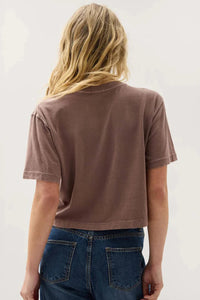 Person wearing a brown t-shirt and blue jeans against a white background.