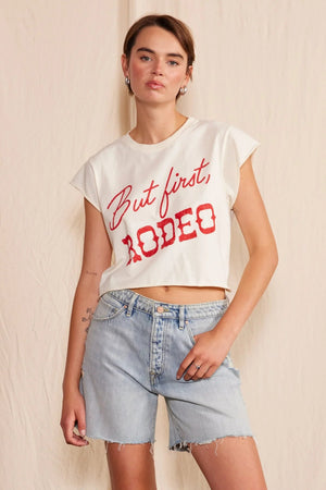 A woman wearing a white shirt with red lettering, and denim shorts.