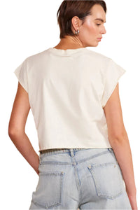The back view of a woman wearing a white shirt with denim shorts.