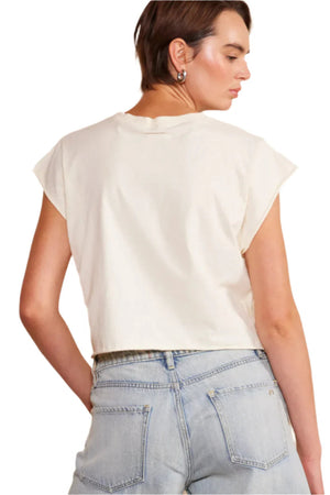 The back view of a woman wearing a white shirt with denim shorts.