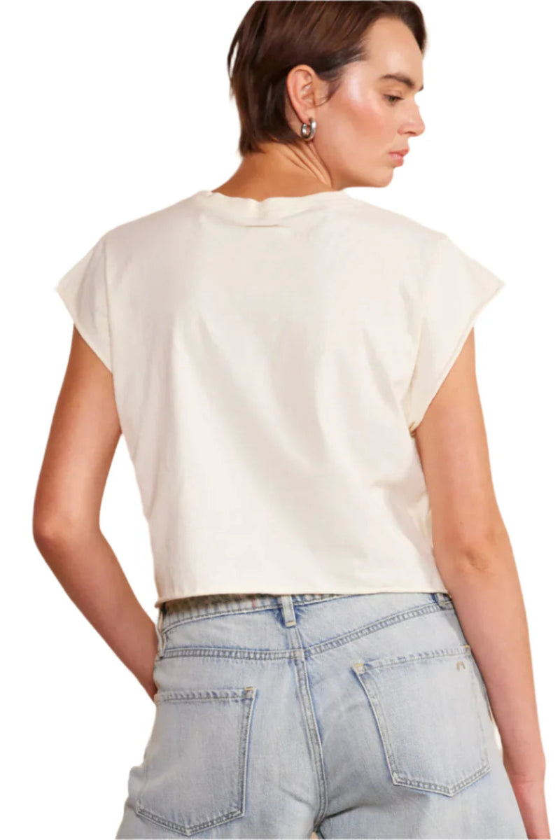 The back view of a woman wearing a white shirt with denim shorts.