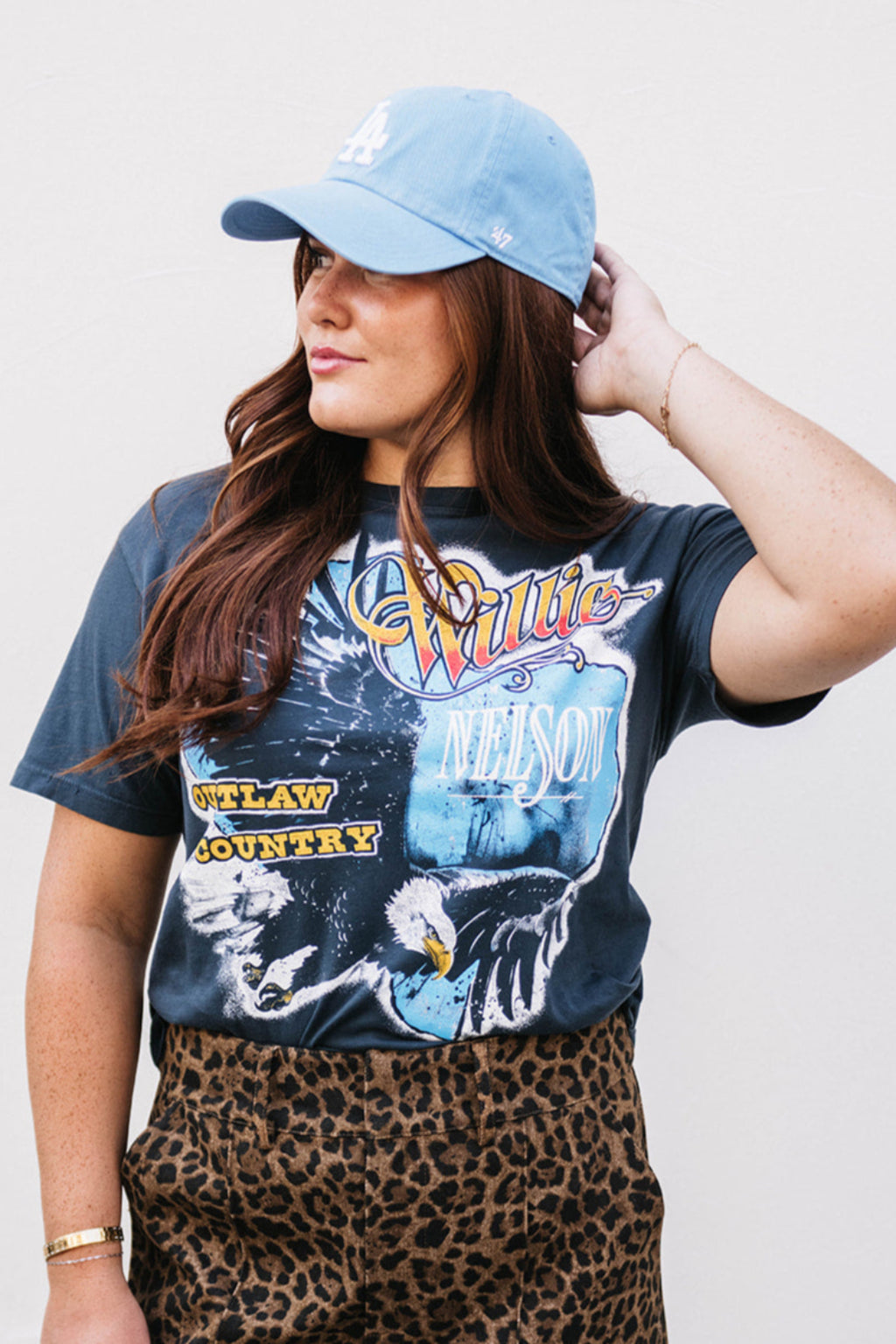 Woman wearing a graphic t-shirt and leopard print skirt with a plain background
