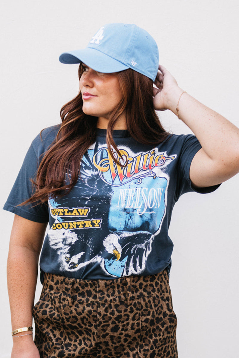 Woman wearing a graphic t-shirt and leopard print skirt with a plain background