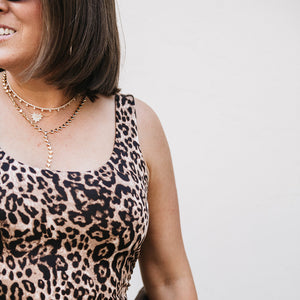 Person wearing a leopard print top with a plain background
