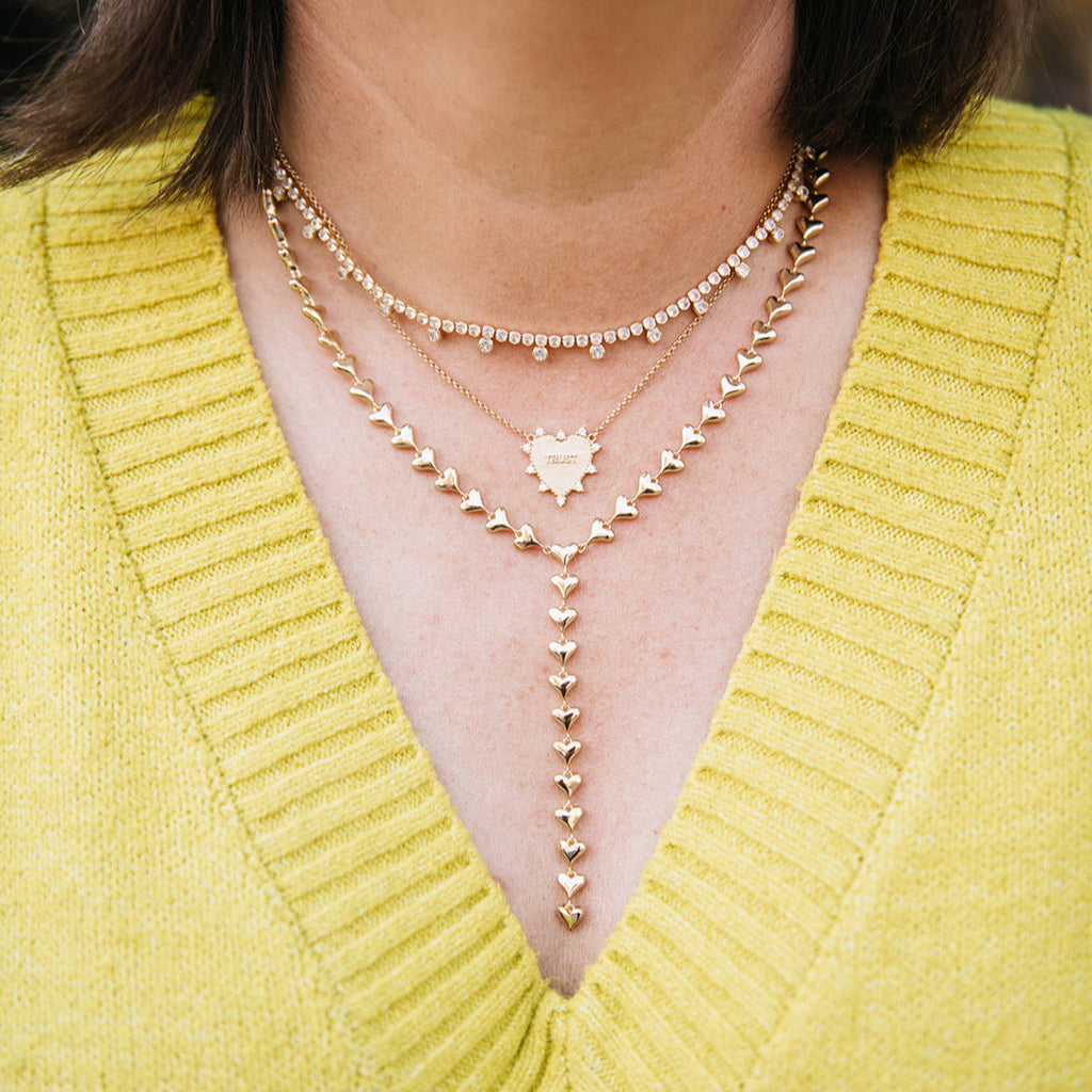 Close-up of a person wearing a yellow sweater and multiple necklaces.