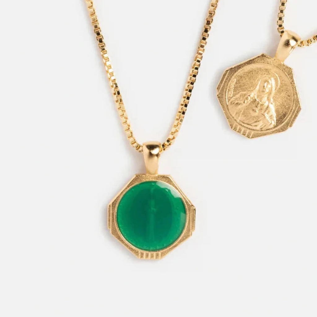 Gold necklace with a green pendant and another gold pendant on a white background