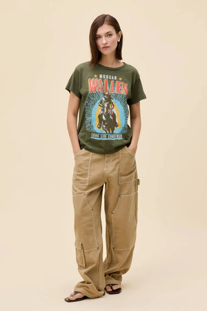 A girl wearing a Morgan Wallen graphic tee with tan pants and black sandals. 