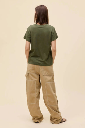A back view of a girl wearing a Morgan Wallen graphic tee with tan pant and black sandals.