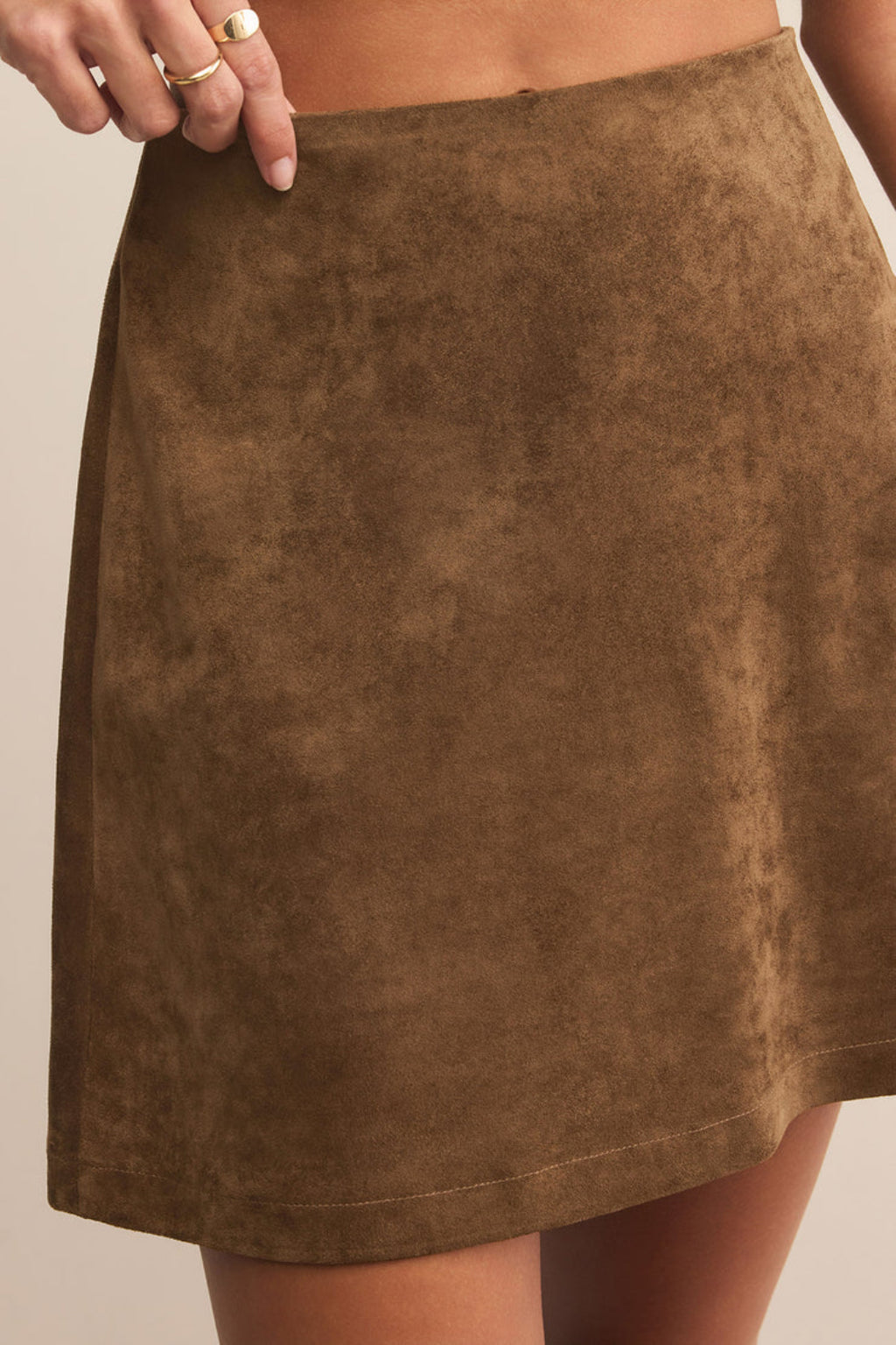 Brown suede skirt worn by a person on a neutral background.