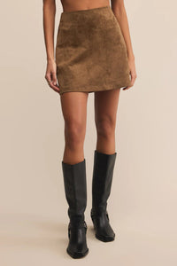 Woman wearing a dark tan skirt and black boots.