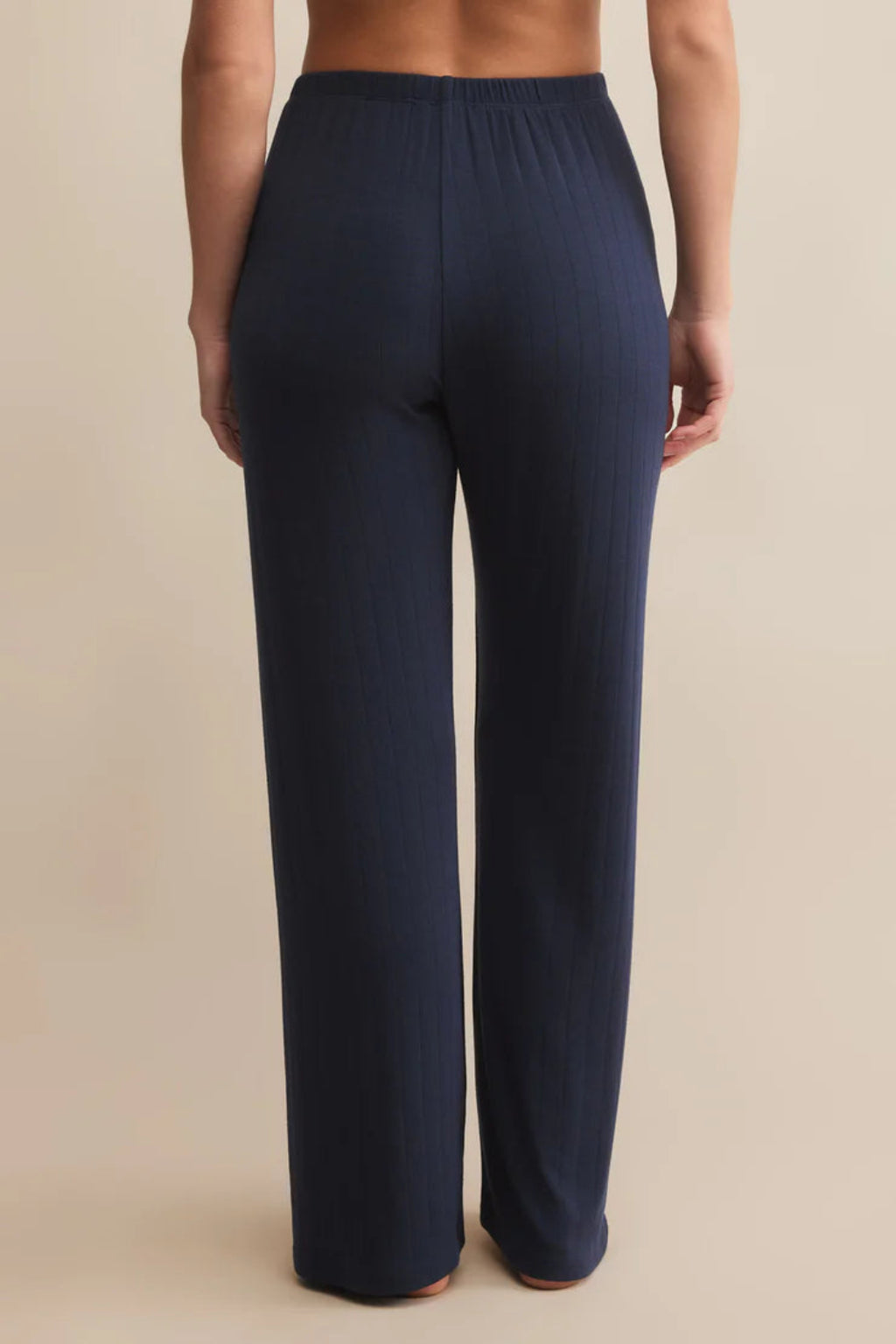 Navy blue pants worn by a person on a beige background.