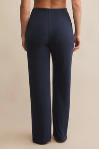 Navy blue pants worn by a person on a beige background.