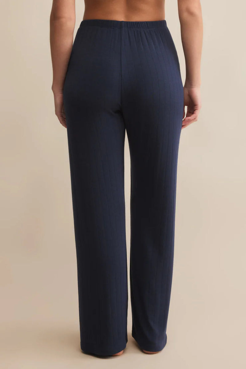 Navy blue pants worn by a person on a beige background.