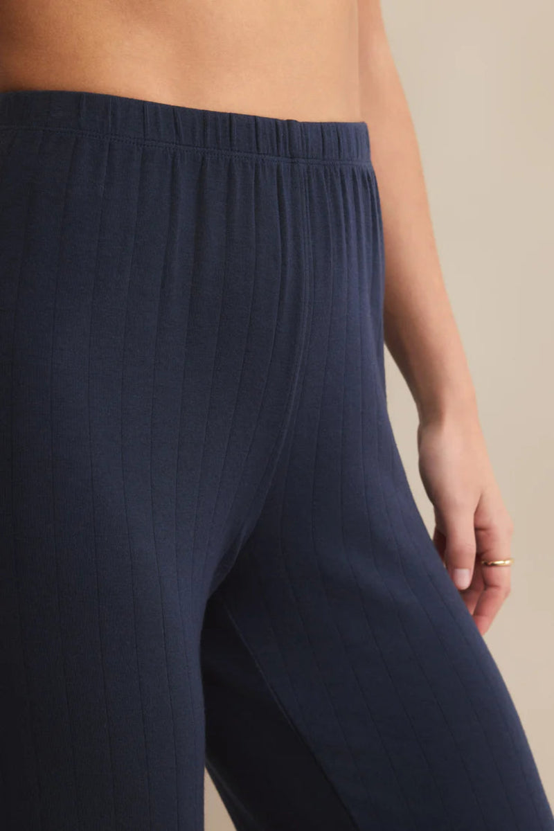 Navy blue pants worn by a person on a beige background.