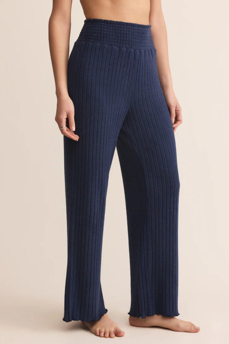 Navy ribbed pants worn by a person on a beige background.