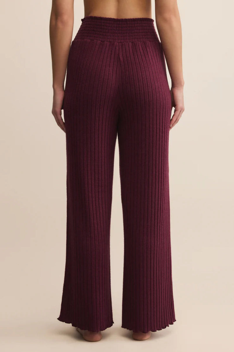 Maroon ribbed pants worn by a person on a beige background.