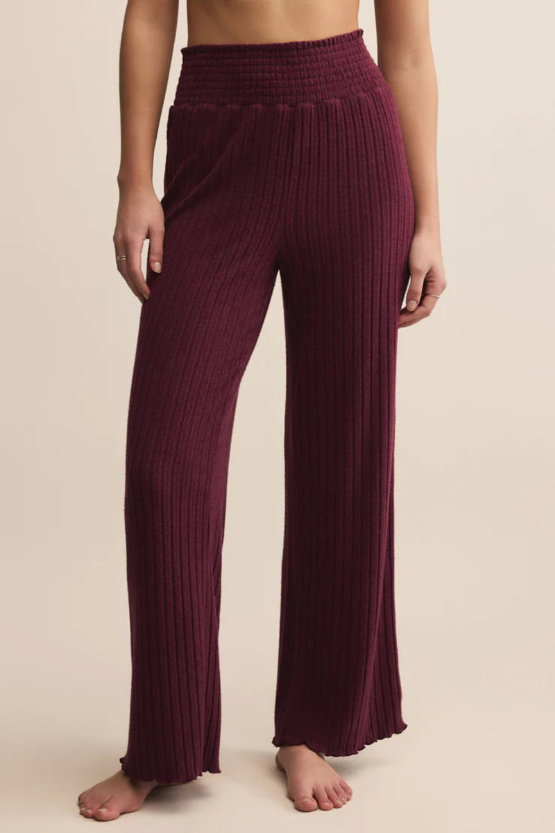 Maroon ribbed pants worn by a person on a beige background.