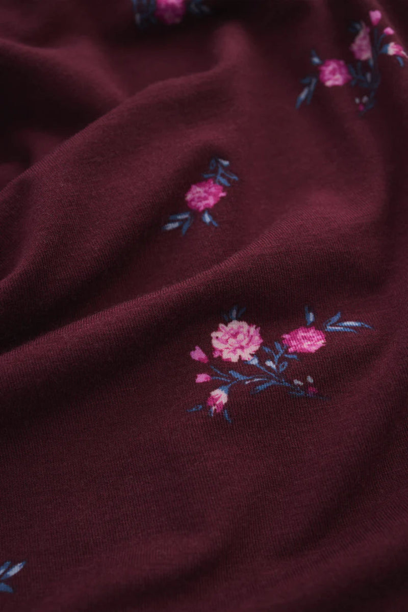 Close-up of a dark fabric with pink floral embroidery.