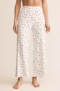 White pajama pants with a subtle pattern worn by a person on a beige background.