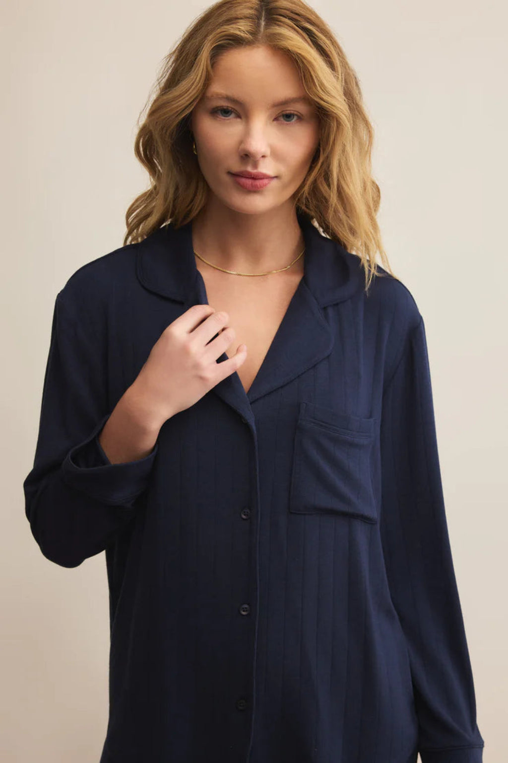 Woman wearing a navy blue shirt against a beige background.