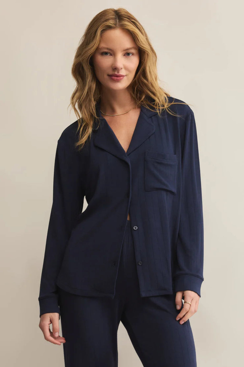 Woman wearing a navy blue pajama set against a beige background.