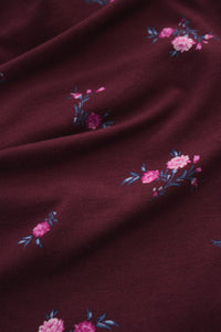 Dark red fabric with pink floral embroidery. 
