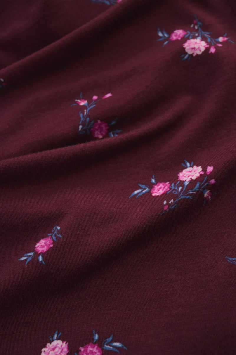 Dark red fabric with pink floral embroidery. 