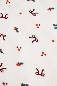 Pattern of red bows and berries on a white background.