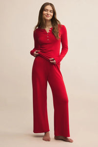 Woman wearing a red pajama set against a beige background.
