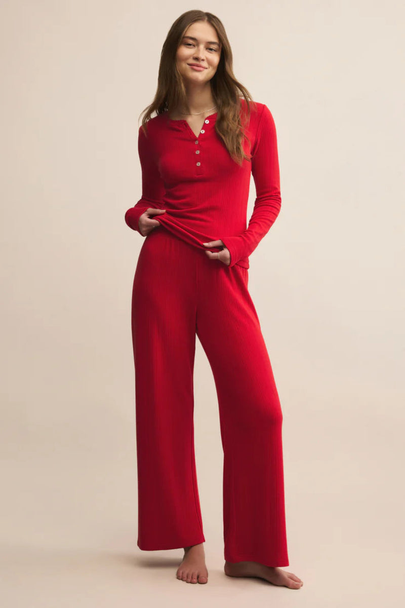 Woman wearing a red pajama set against a beige background.