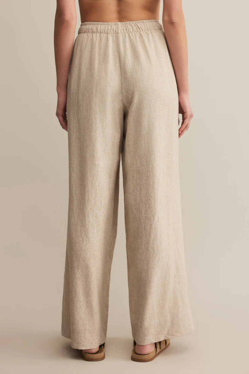 A back view of a woman wearing a tan linen pair of pants.