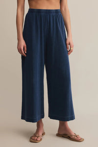 Navy blue wide-leg pants worn by a person on a beige background.