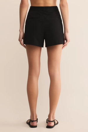 The back view of a woman wearing a black pair of shorts and black sandals.