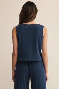 Woman wearing a sleeveless navy top and pants on a beige background.