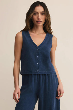 Woman wearing a blue sleeveless top and pants on a beige background.