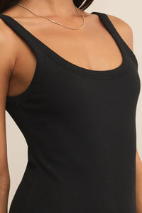 Black tank top worn by a person on a beige background.