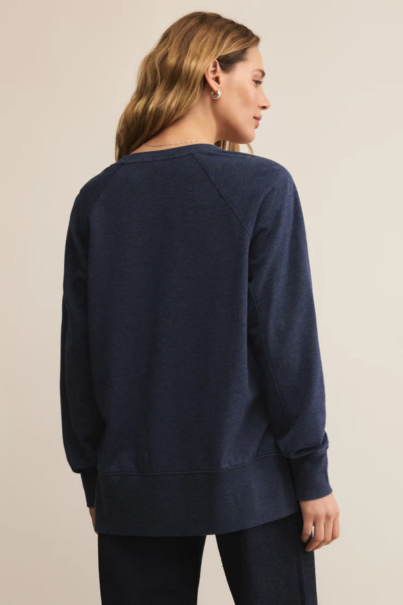 Woman wearing a navy blue sweatshirt against a beige background.
